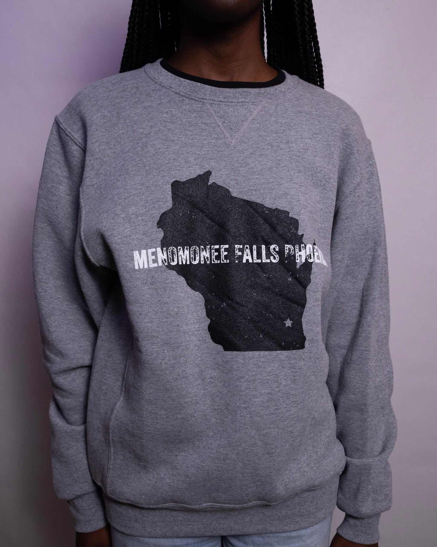 Person wearing a gray sweatshirt with a graphic design on a plain background